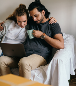 a man and woman sitting on a couch and using a lapto